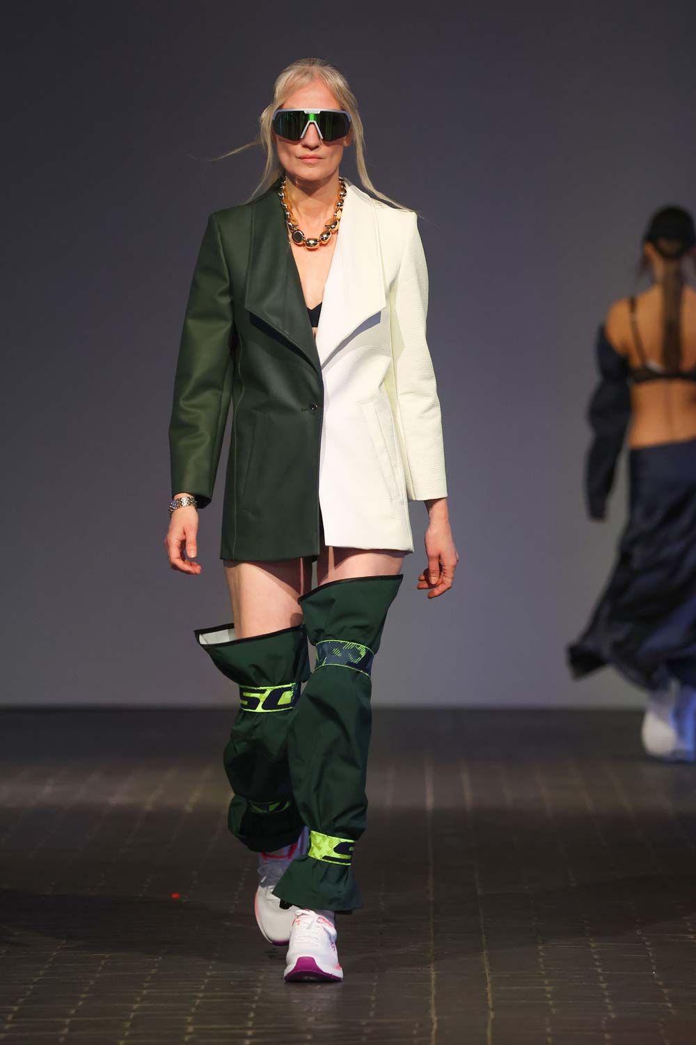 Rebekka Ruétz Modenschau Berlin Fashion Week – recyceltes Outfit in Grün-Schwarz mit Kopfhörer und Skibrille